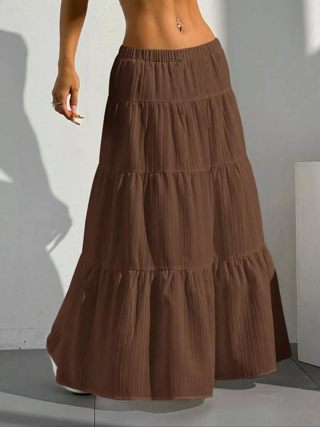 Brown tiered maxi skirt with shadow on white wall