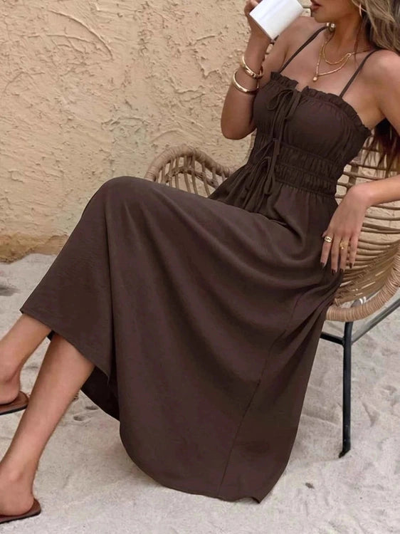 Woman in a brown dress sitting on a wicker chair outdoors. Leaning back.