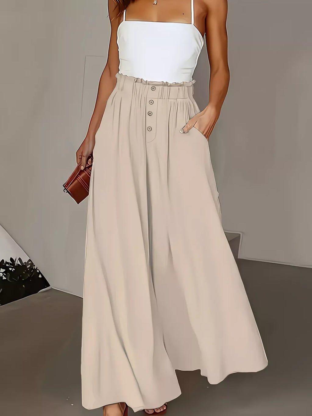 Woman wearing a white top and beige skirt with a brown clutch against a neutral background