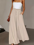 Woman wearing a white top and beige skirt with a brown clutch against a neutral background