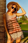 Woman wearing a sleeveless dress with an American flag design and sunglasses, standing next to a palm tree.