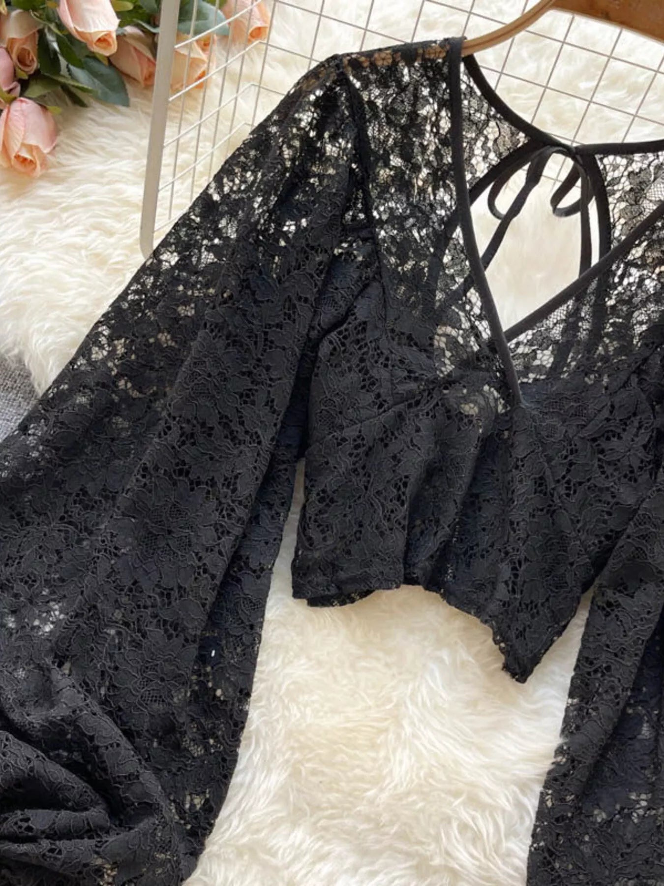 Black lace top on a white surface with flowers in the background