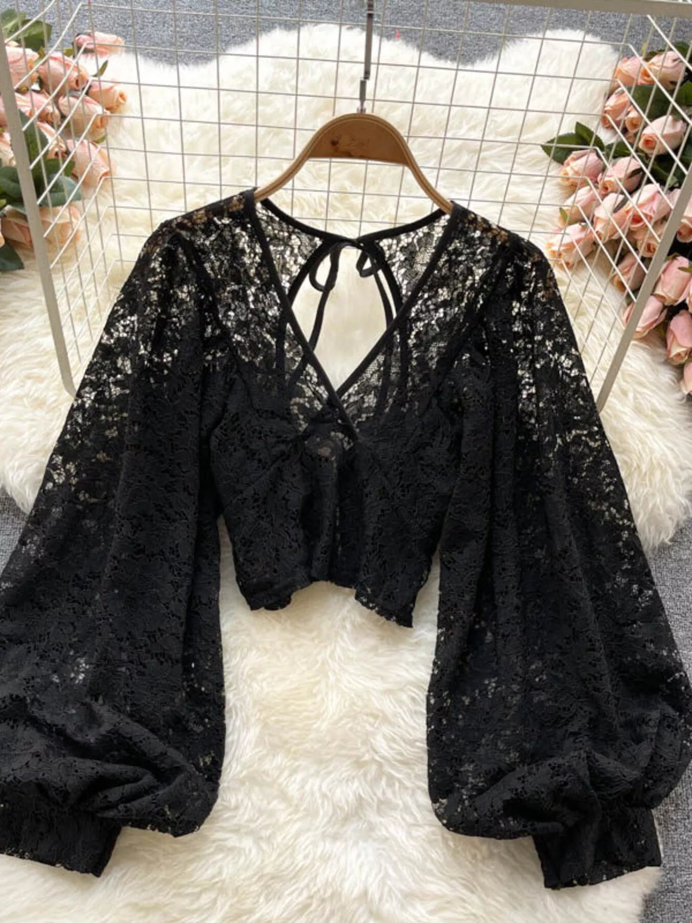 Black lace top on a hanger with floral decorations in the background