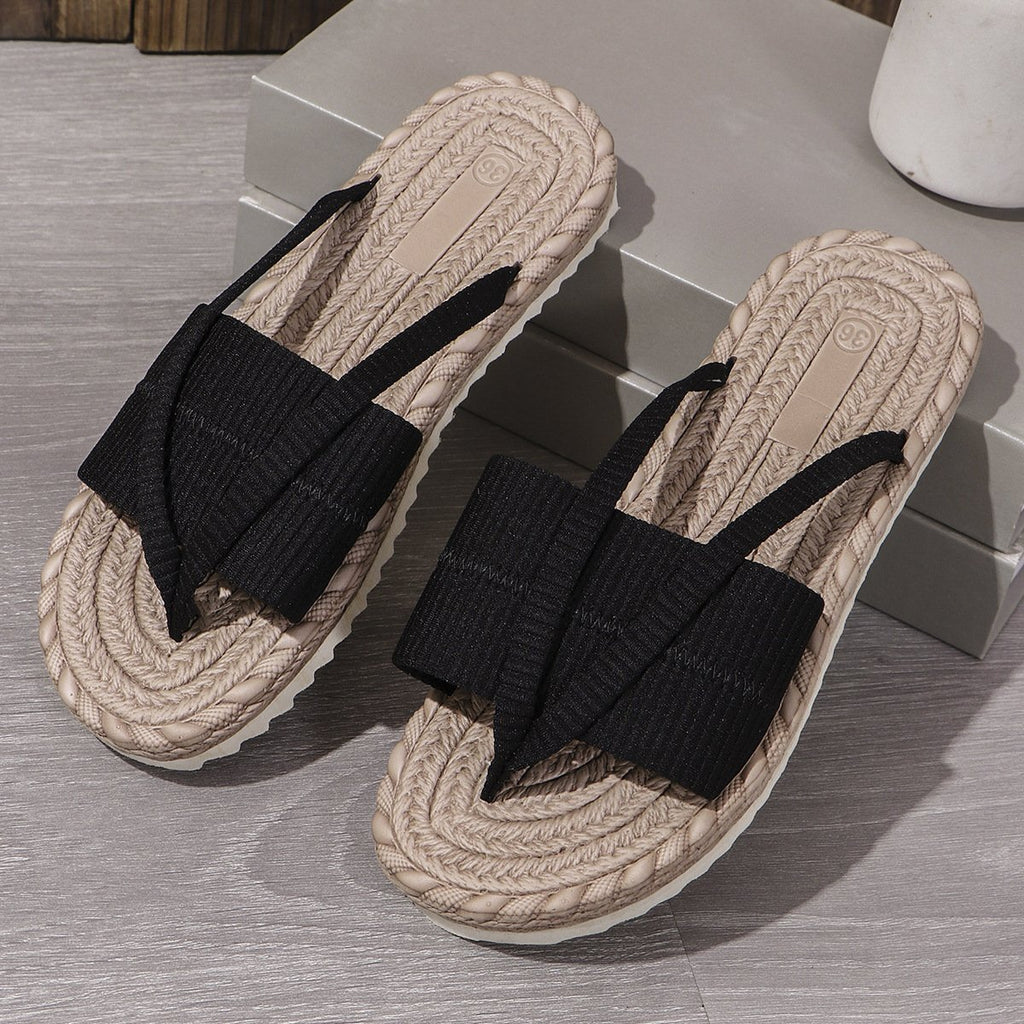 Pair of sandals with black straps on a wooden floor