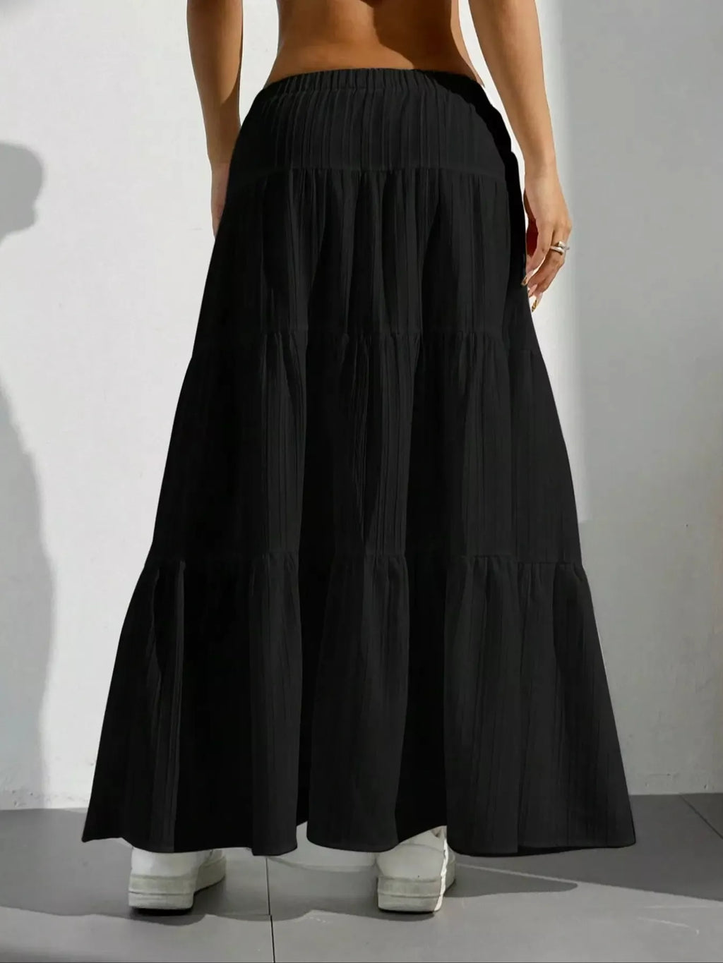 Black tiered maxi skirt with shadow on white wall