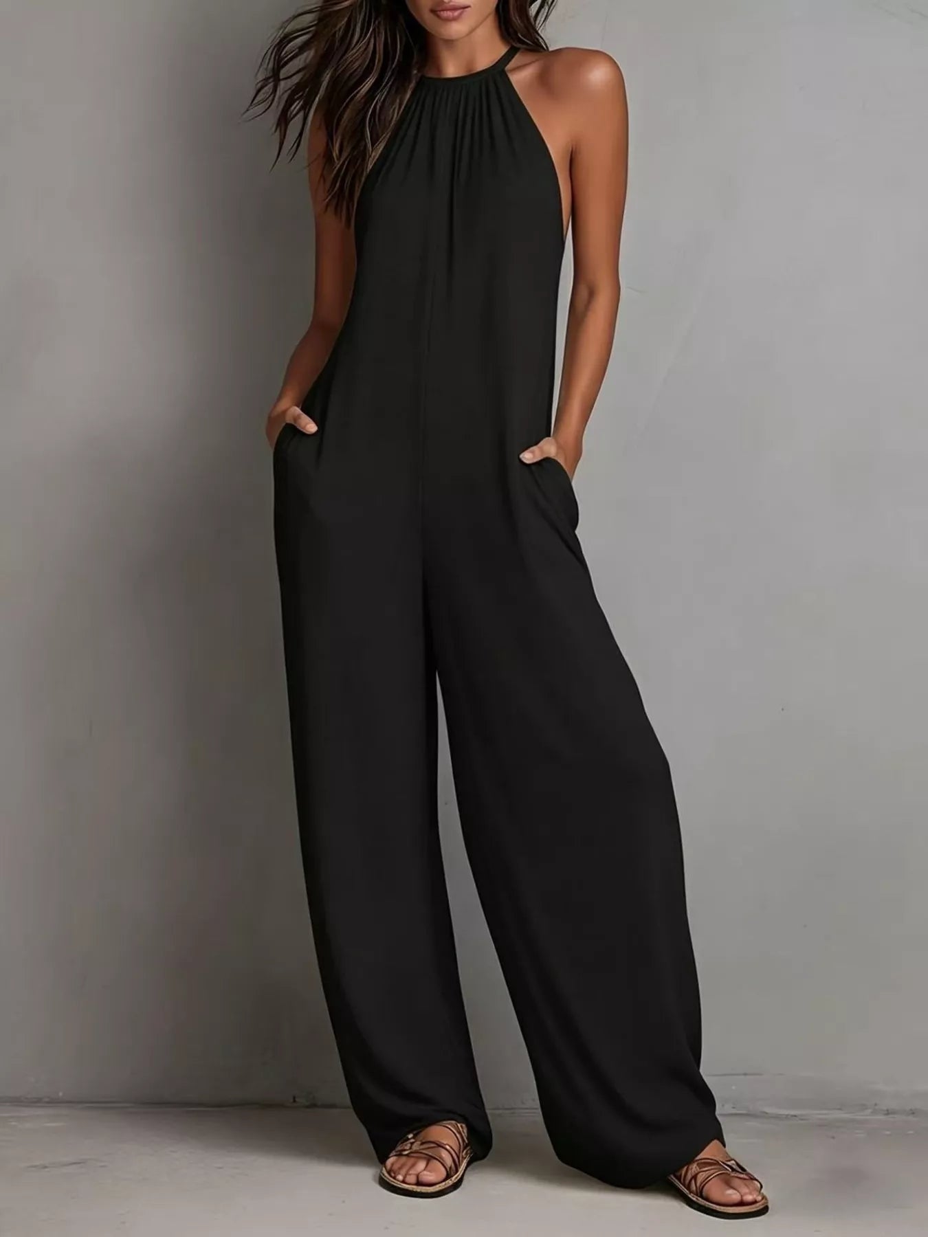Woman wearing a black jumpsuit against a gray background