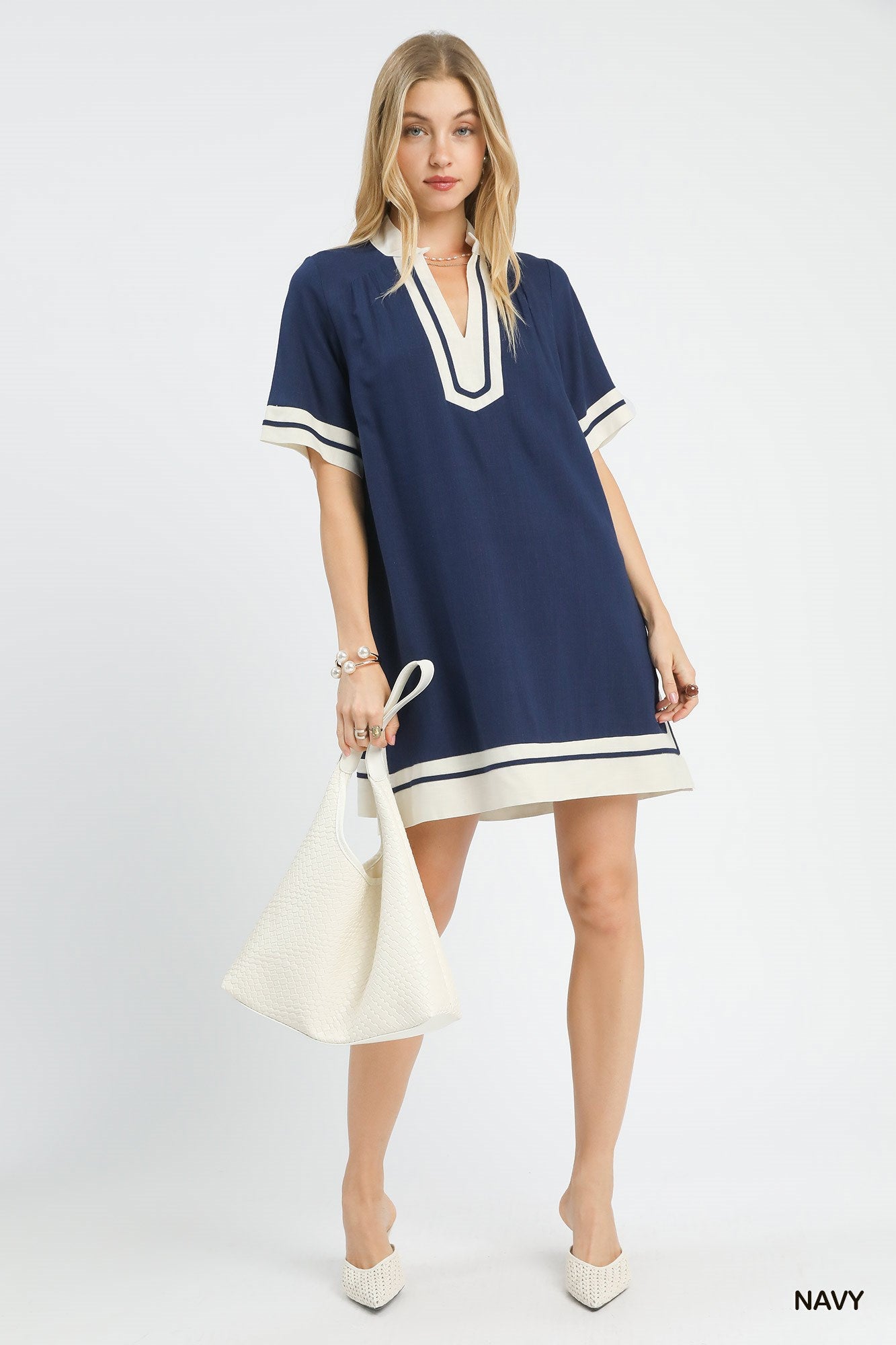 Woman wearing a navy dress with white trim on a white background