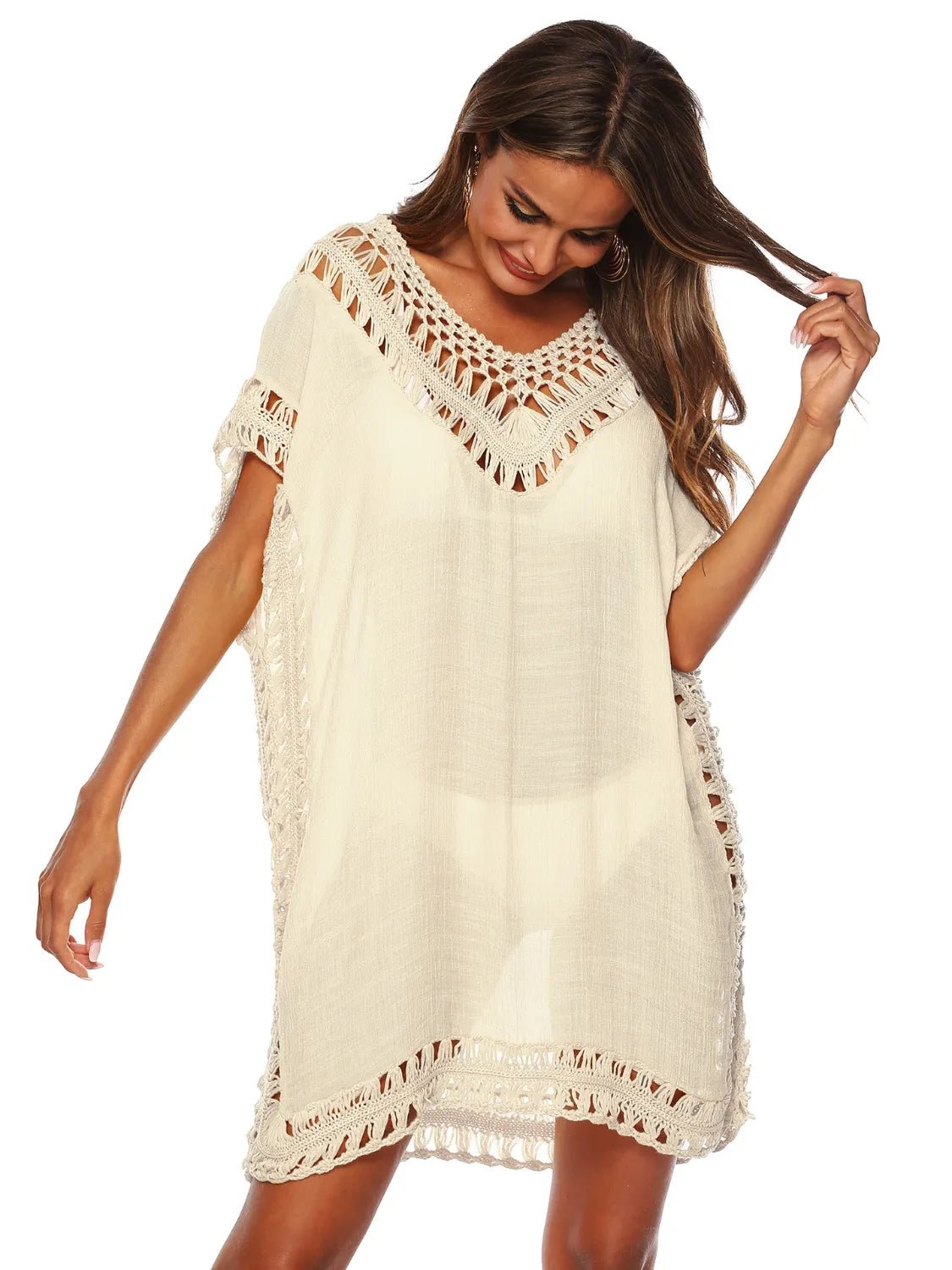 Woman looking at the floor wearing a white crochet cover-up dress on a white  background
