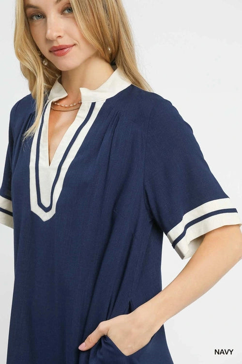 Woman wearing a navy dress with white trim on a white background