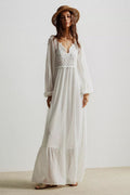 Woman wearing a white dress with lace detailing and a straw hat on a plain background