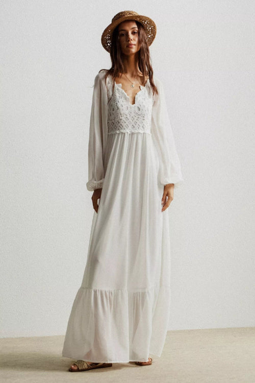Woman wearing a white dress with lace detailing and a straw hat on a plain background
