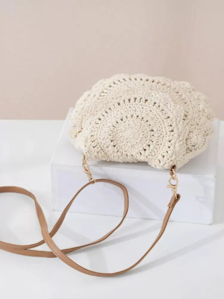 Crocheted handbag with a brown strap on a white surface