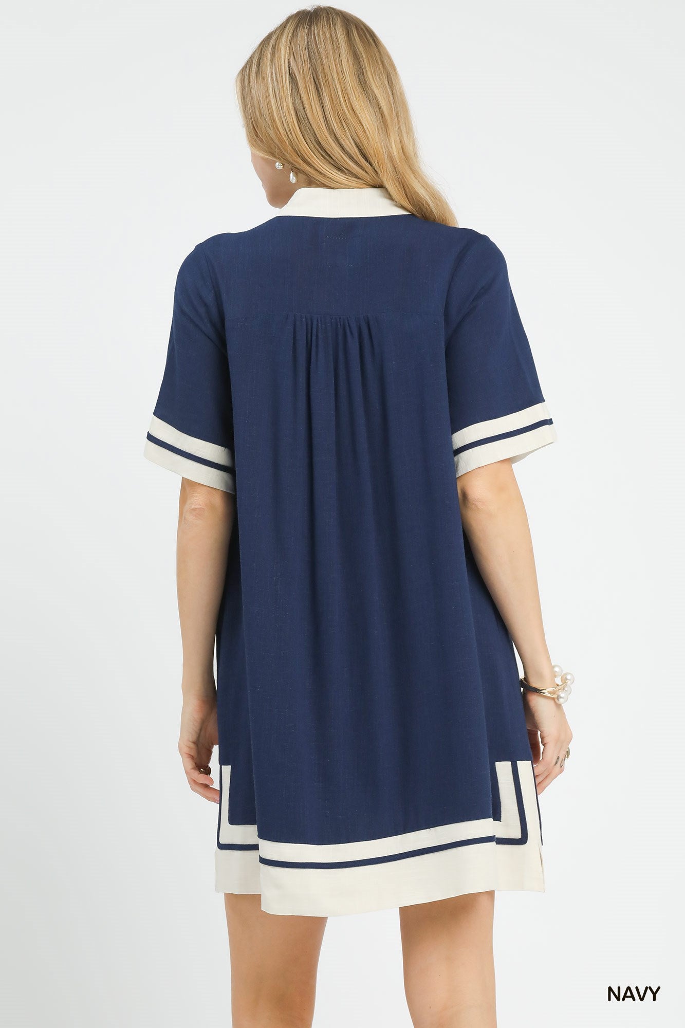 Navy dress with white trim worn by a model on a light gray background