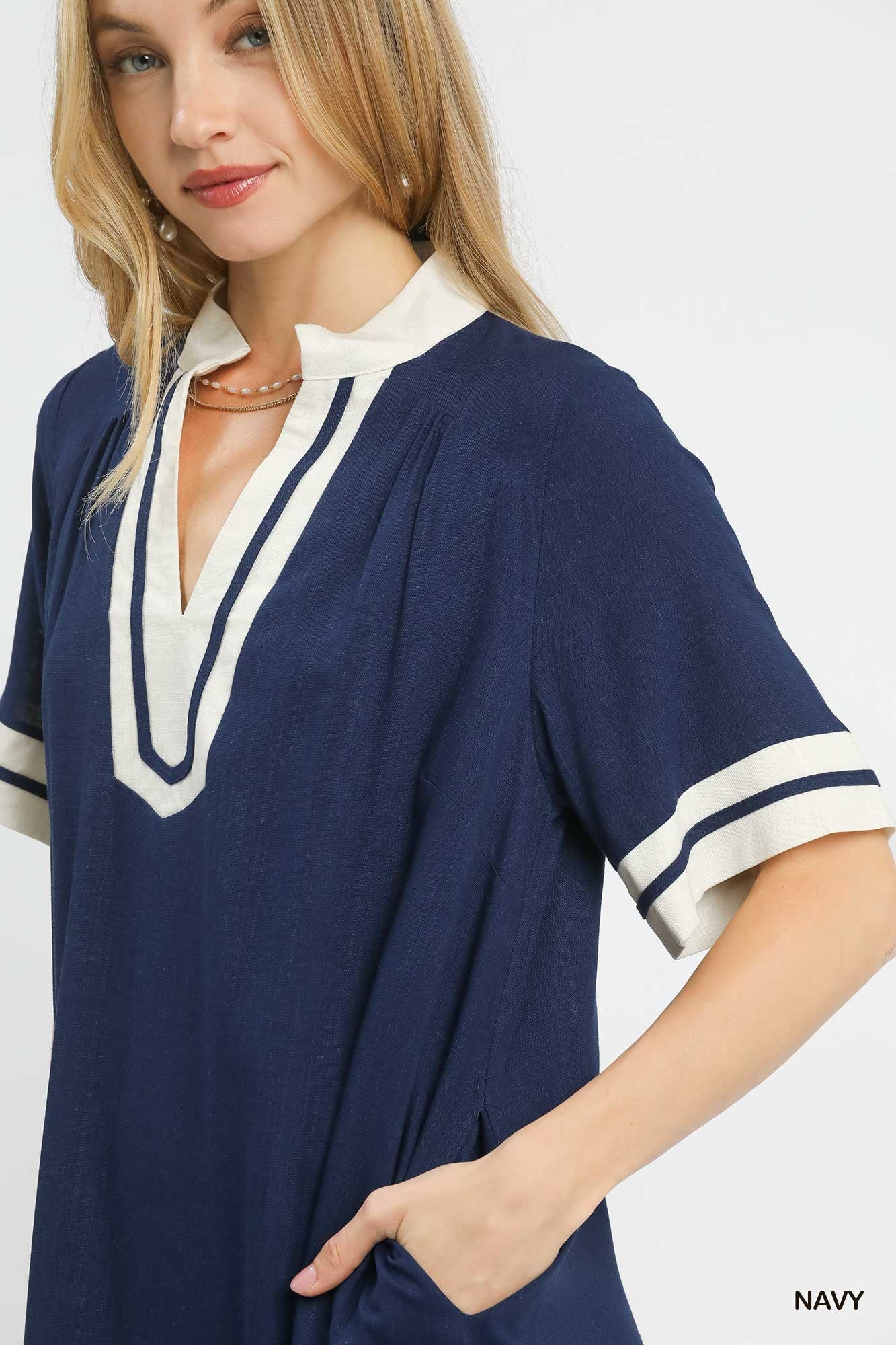 Woman wearing a navy dress with white trim on a white background