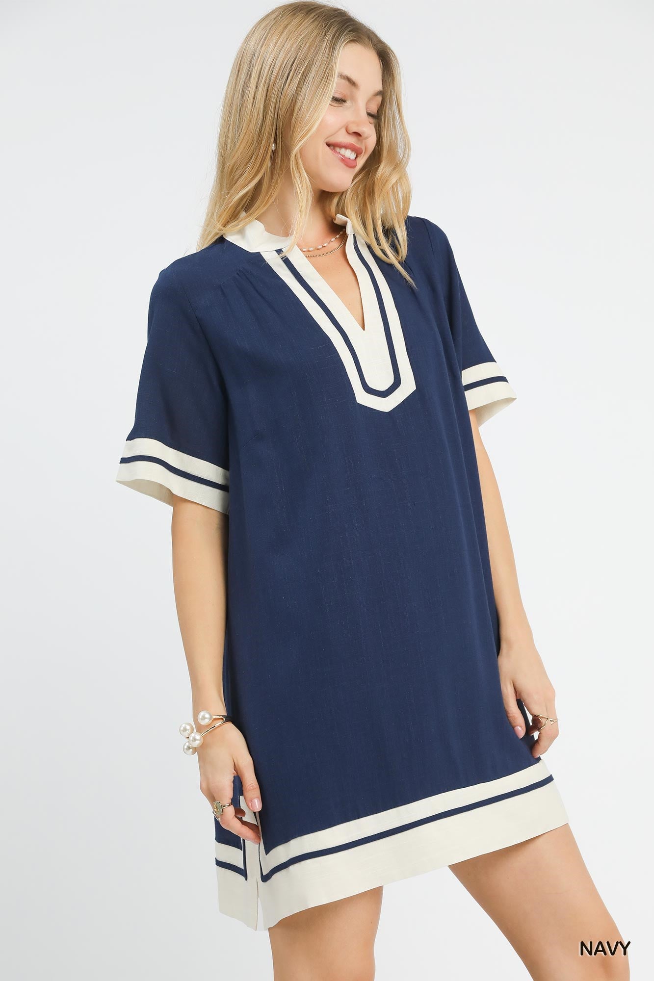Woman wearing a navy dress with white trim on a white background