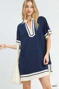 Woman wearing a navy and white dress with a plain background