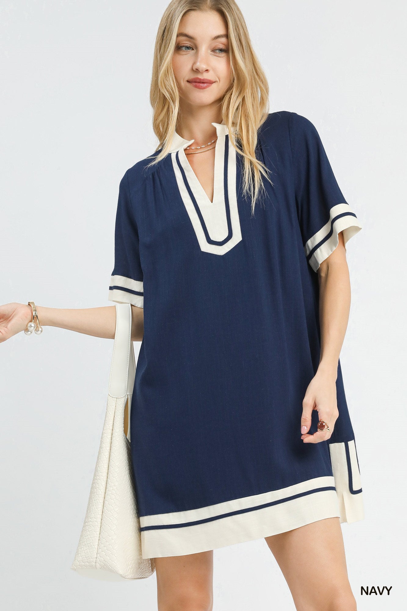 Woman wearing a navy and white dress with a plain background