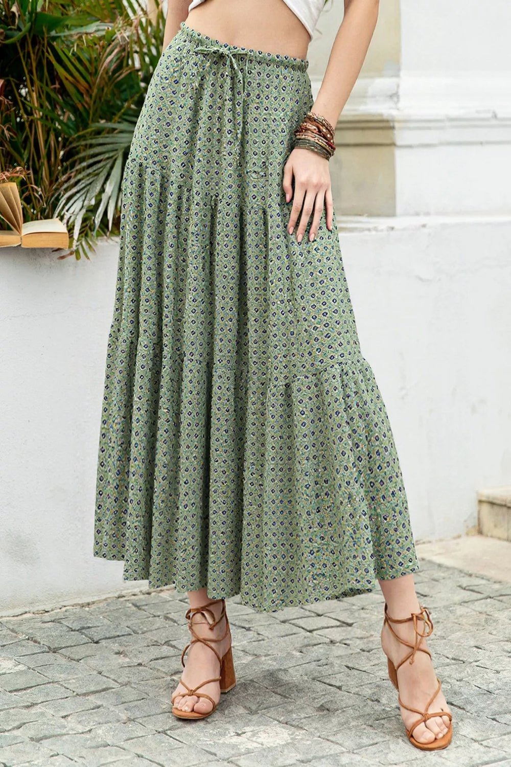 Person wearing a green patterned skirt standing outdoors.