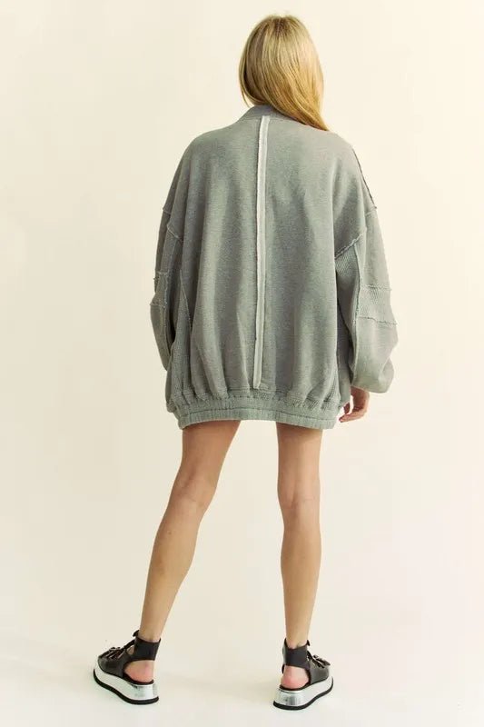 Person wearing a gray oversized sweater on a beige background
