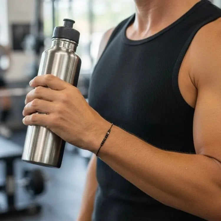Person holding a silver water bottle in a gym setting