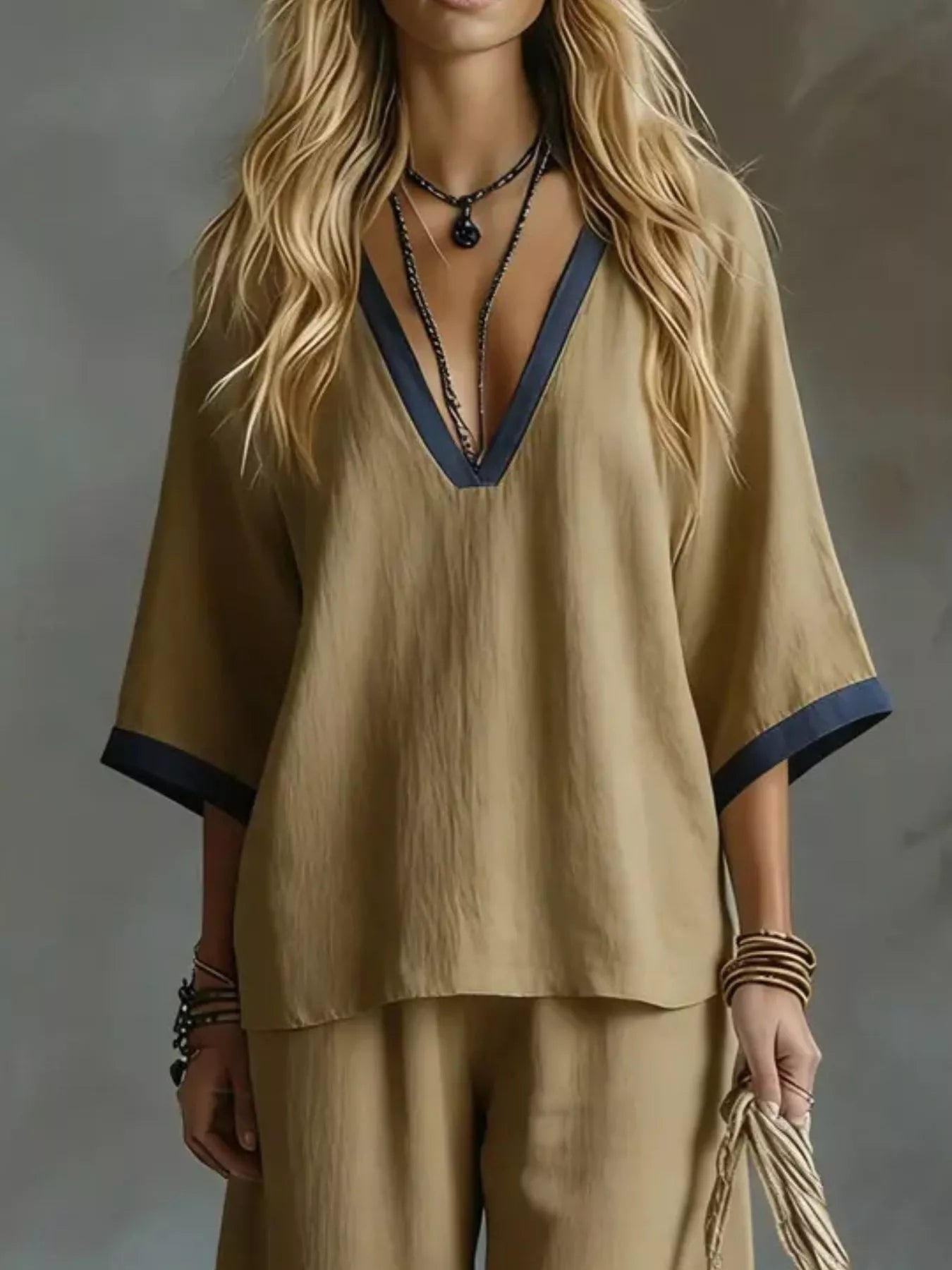Woman wearing a beige outfit with a deep neckline against a gray background