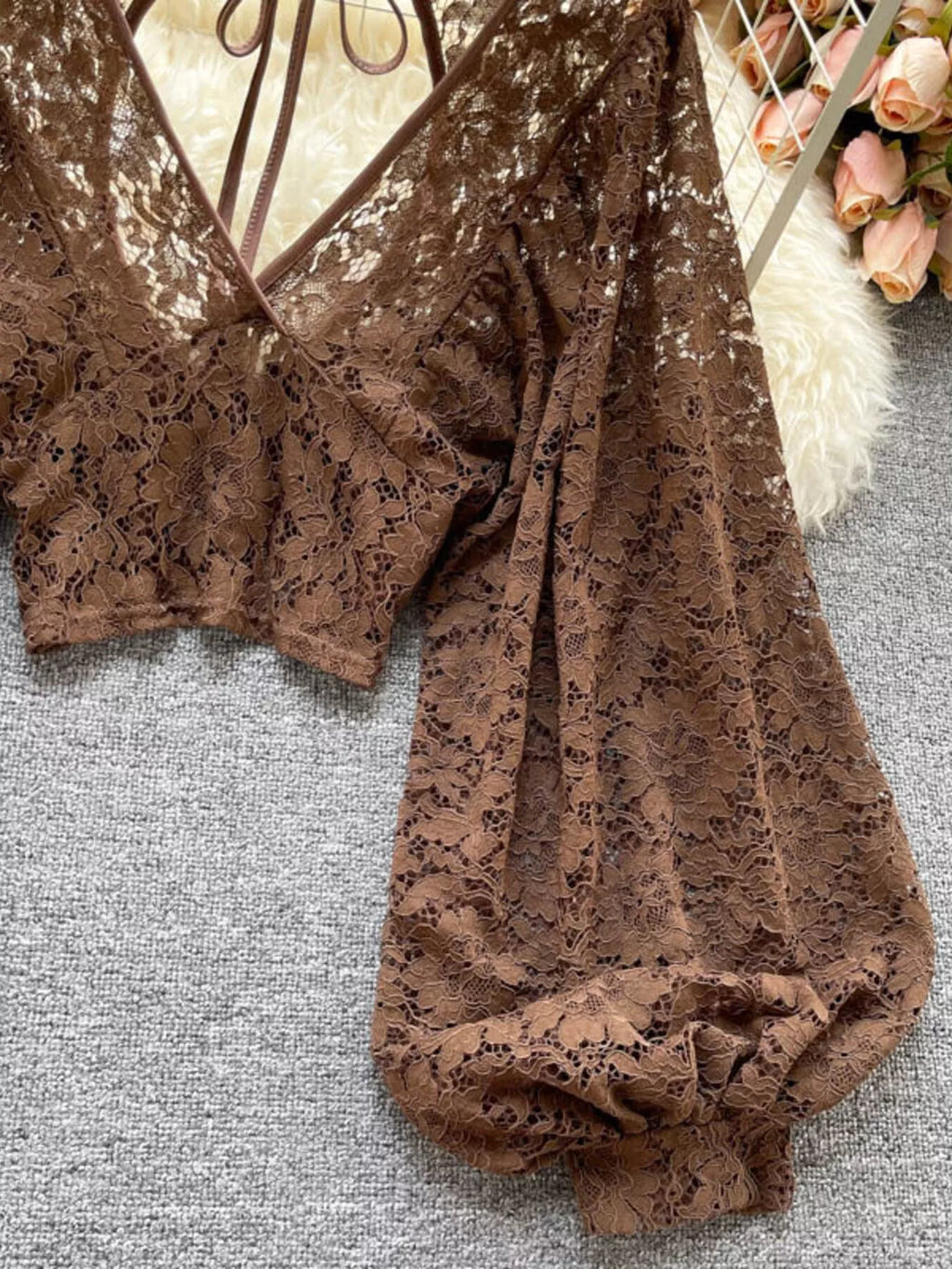 Brown lace top on a textured surface with flowers in the background