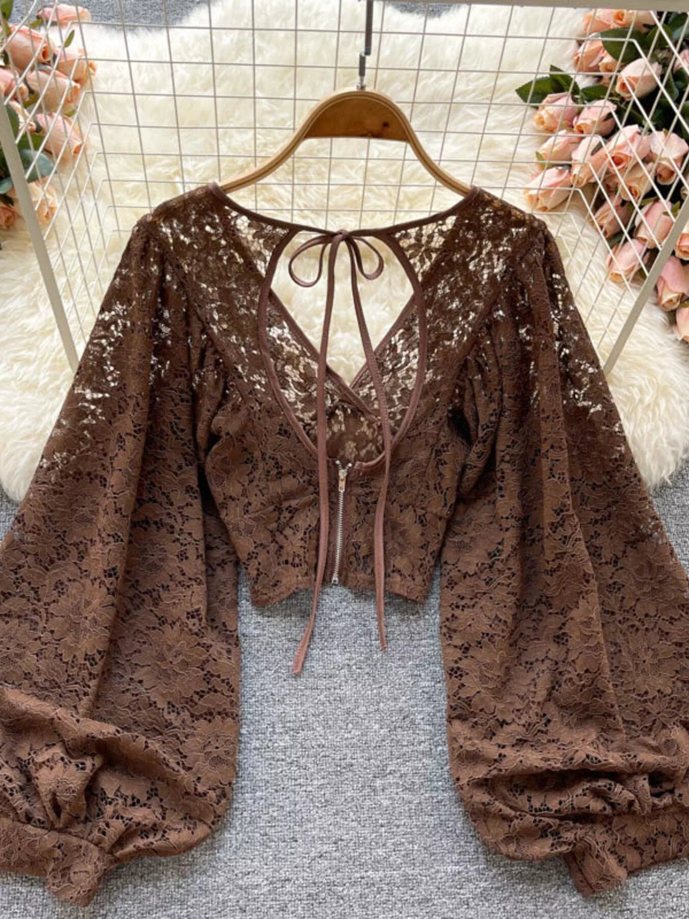 Brown lace top on a hanger with floral decorations in the background
