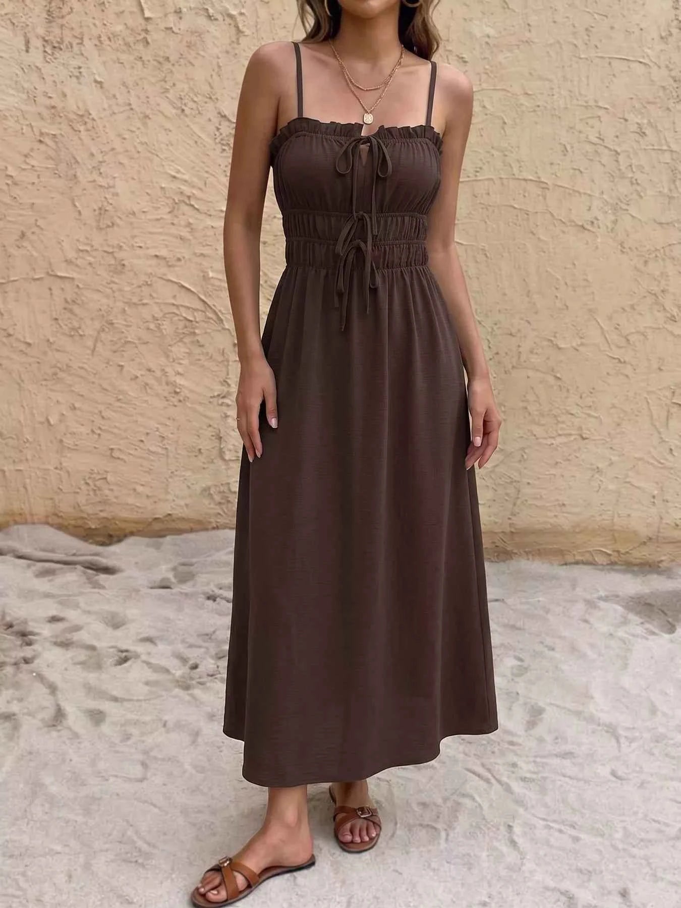 Woman wearing a brown dress standing against a beige wall.