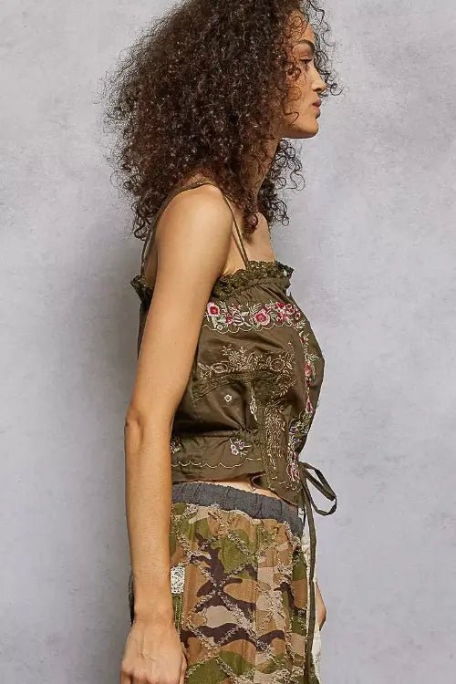 Woman wearing a camouflage dress with floral details against a gray background
