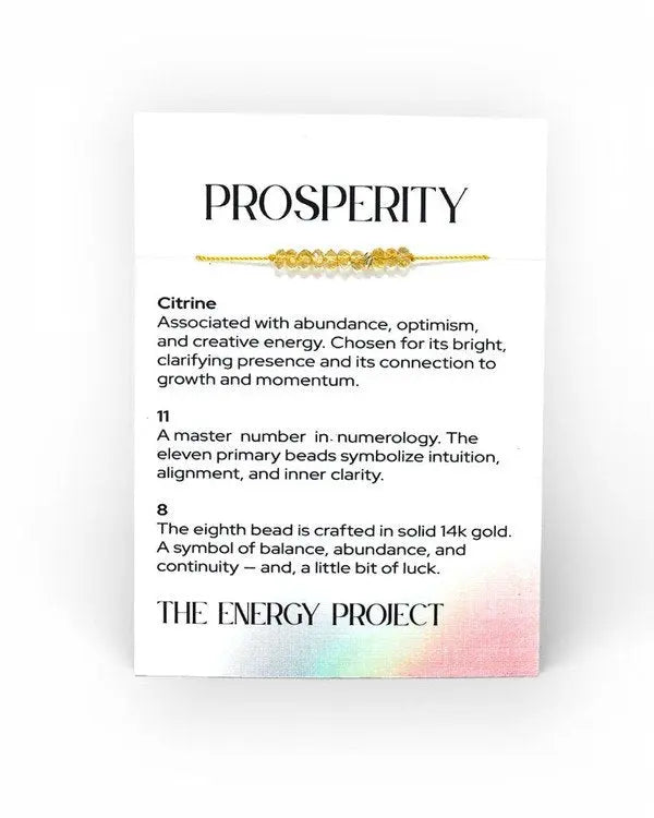 Bracelet with gold beads on a card detailing its properties, associated with abundance, optimism, and creative energy.