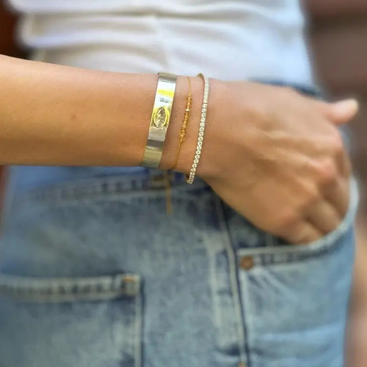 Close-up of a person's wrist wearing multiple bracelets with a blurred background
