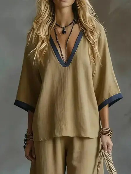 Woman wearing a beige outfit with a deep neckline against a gray background