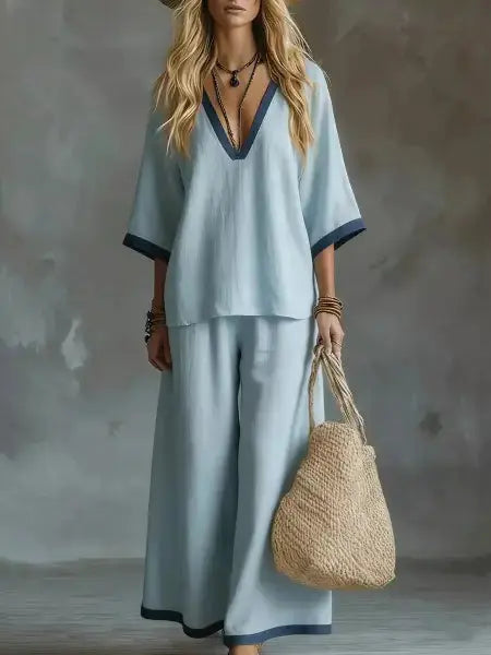 Woman in light blue outfit holding a woven bag against a neutral background