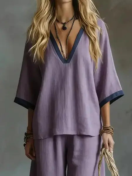 Person wearing a purple outfit with a deep neckline against a neutral background