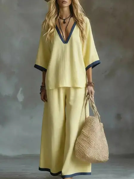 Woman in a yellow outfit holding a woven bag against a textured gray background