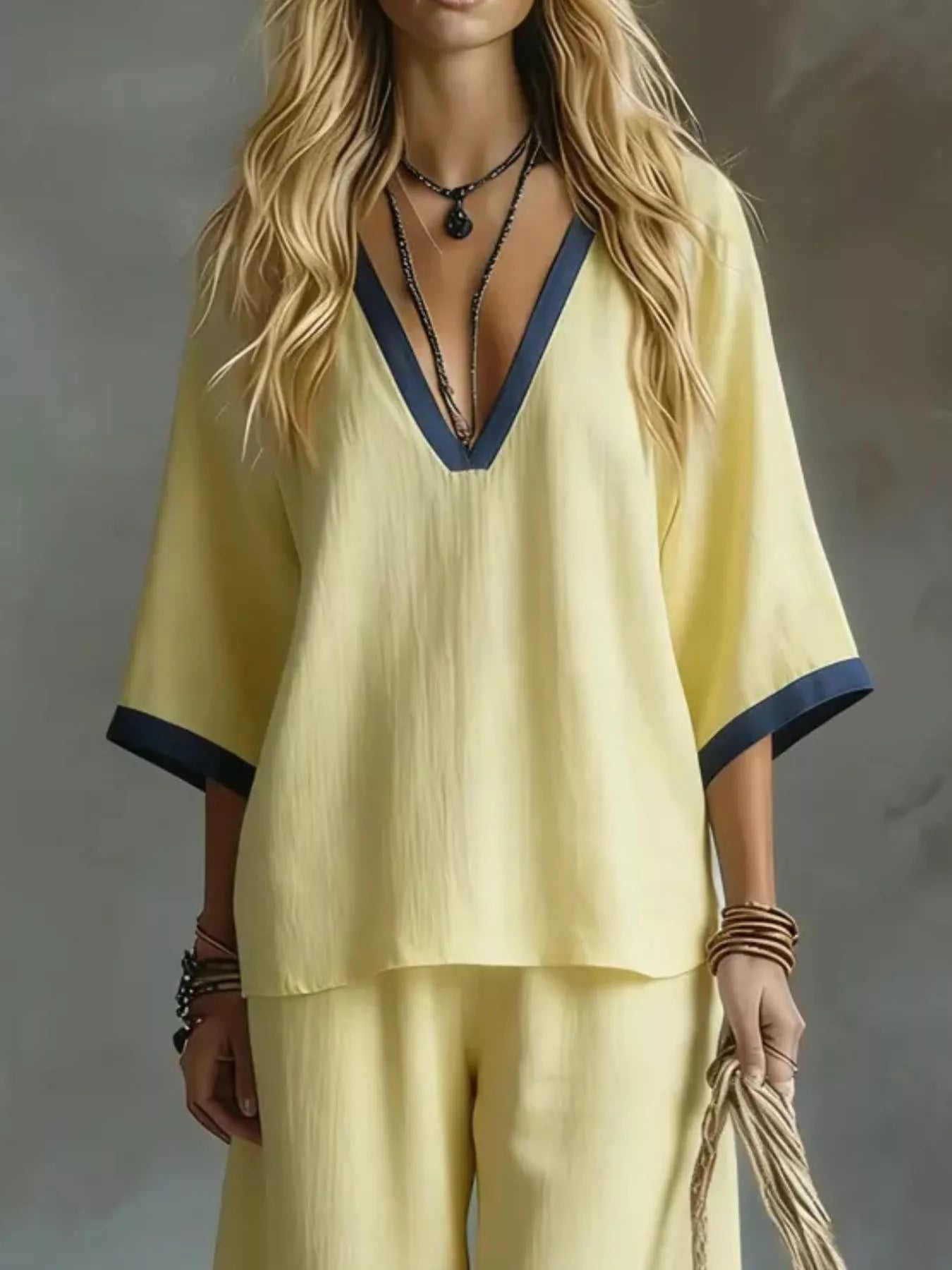 Woman wearing a yellow outfit with blue trim against a gray background