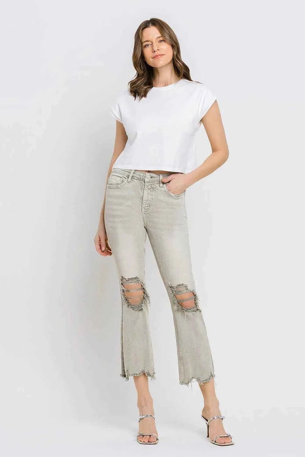 Woman wearing a white t-shirt and light gray ripped jeans on a white background