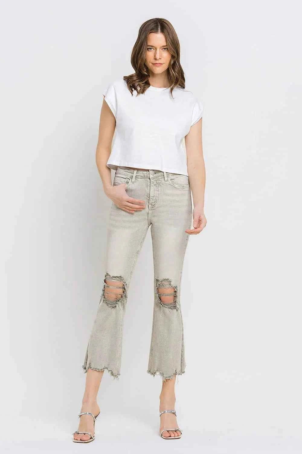 Woman wearing a white t-shirt and light gray flared jeans on a white background