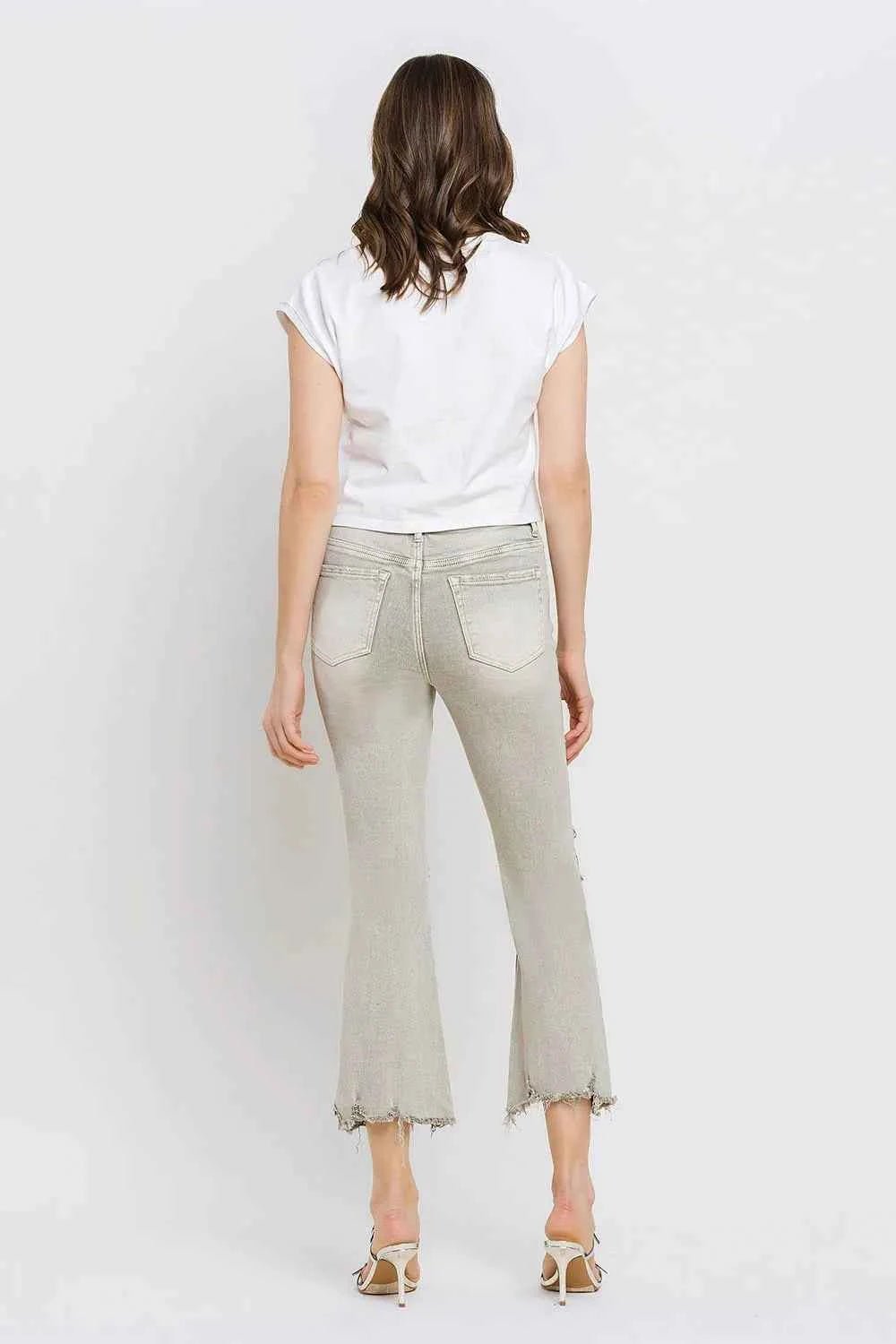 Person wearing light gray pants and a white top facing that wall on a plain background