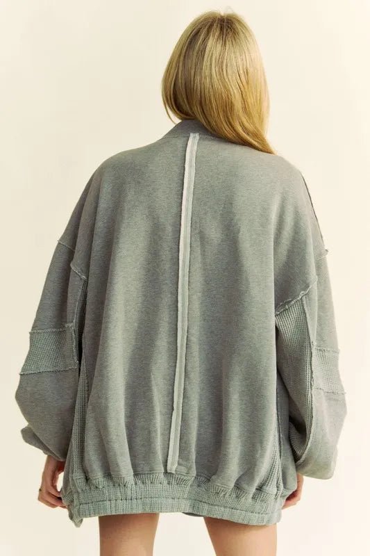 Person wearing a gray oversized sweater on a beige background