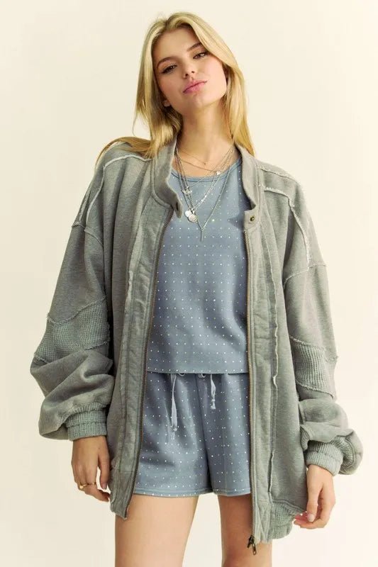 Woman wearing a green jacket over a blue outfit with a white background