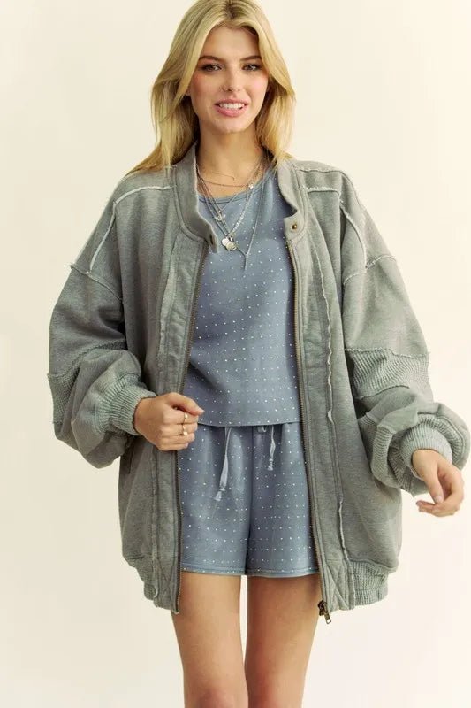 Woman wearing a gray jacket over a blue outfit on a beige background