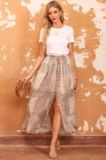 Woman wearing a white top and patterned skirt against a textured orange wall.