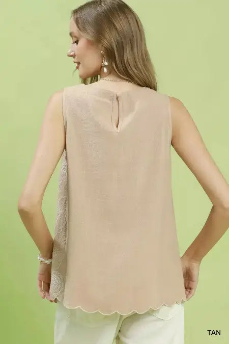 Woman wearing a beige sleeveless top against a light green background