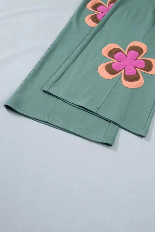 Green fabric with pink and orange floral patterns on a light gray background