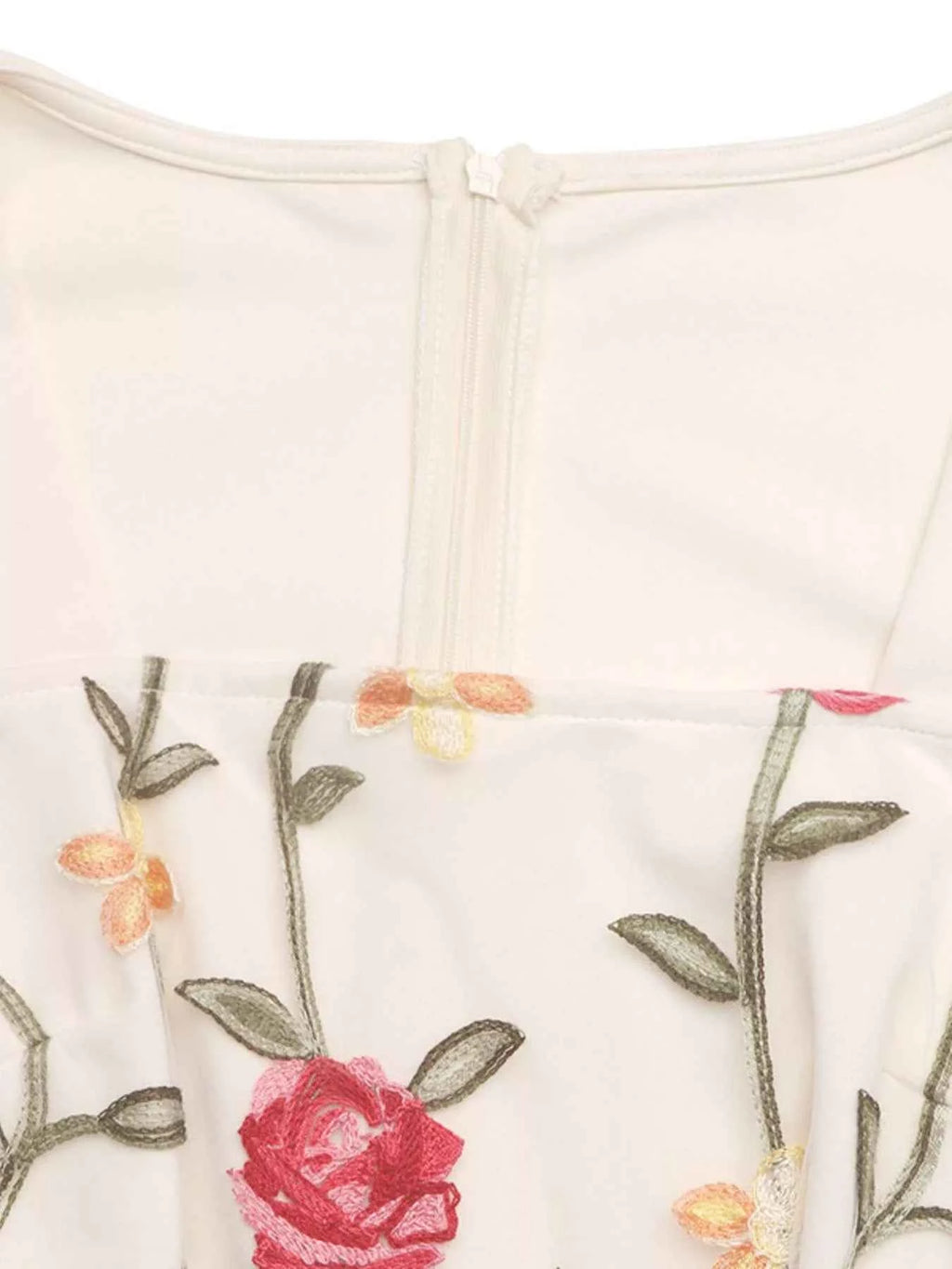 Close-up of a white garment with floral embroidery on a light background
