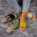 Two pairs of sandals on a stone floor, one with a yellow strap and the other with a green strap.
