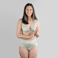Woman wearing a light green bra and panties set on a gray background