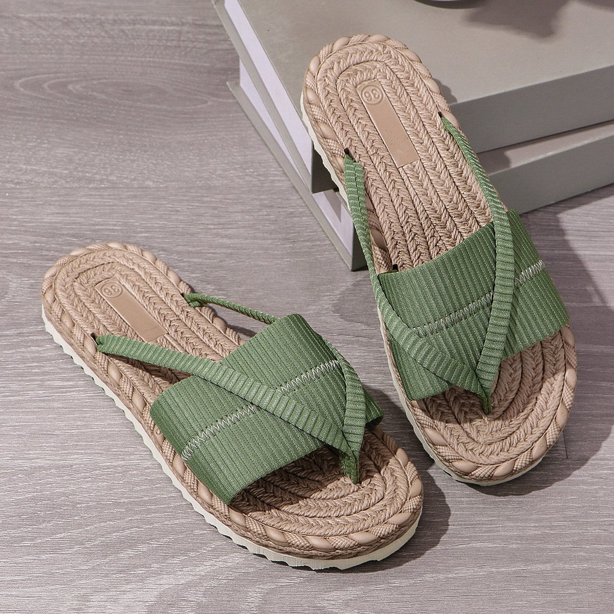 Pair of sandals with green straps on a wooden floor