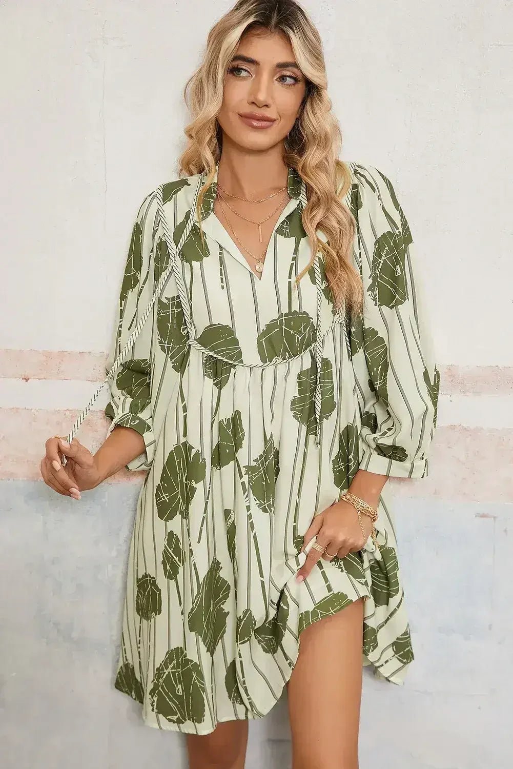 Woman wearing a green leaf-patterned dress against a light background